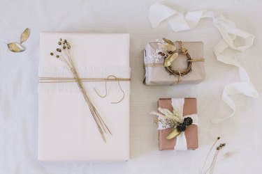 Packages with brown, white, and neutral paper with white ribbon and dried flowers