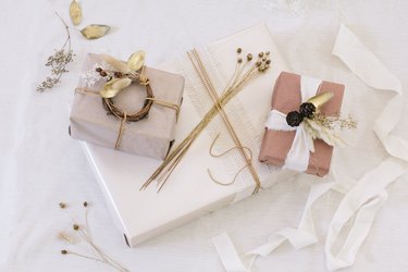Packages with brown, white, and neutral paper with white ribbon and dried flowers