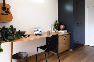 black and wood small home office idea with plants and guitar on the wall