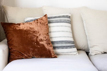 brown velvet pillow with striped neutral pillow on grey couch