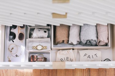 Wrapped sheets, ties, and sunglasses in DIY hikidashi boxes in open drawer of contemporary cabinet against wood flooring