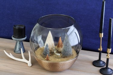 a holiday scene made from a glass lamp globe and bottle-brush trees