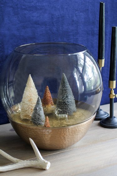 a holiday scene made from a glass lamp globe and bottle-brush trees