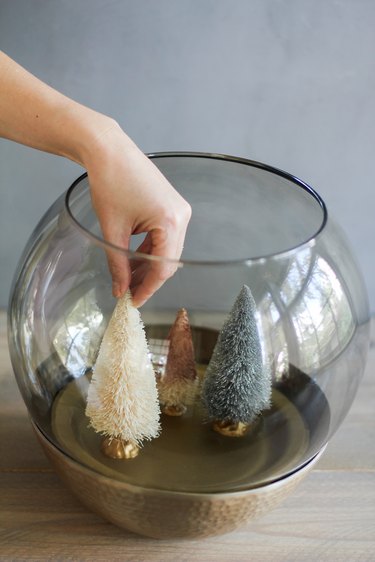 placing bottle-brush trees in the holiday terrarium scene