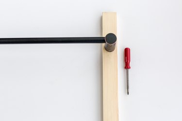Wood board with black towel rod and red screwdriver