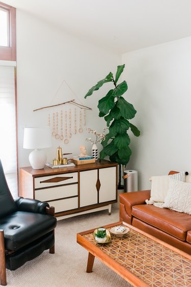 Mid-century leather and wood furniture in white-walled room with plant