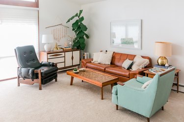 White walled-carpeted living room with retro leather and wood furniture