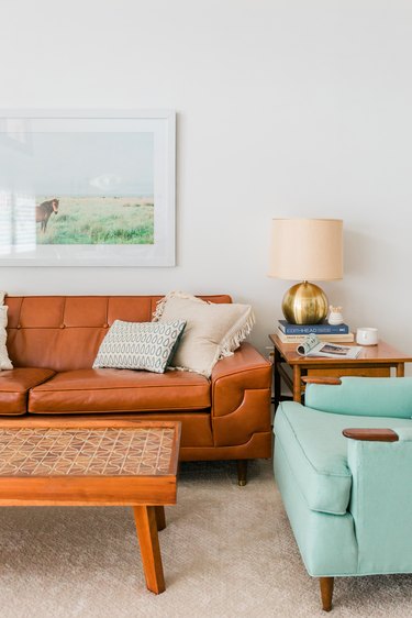 Living room with brown leather sofa, coffee table, side table, and turquoise accent chair