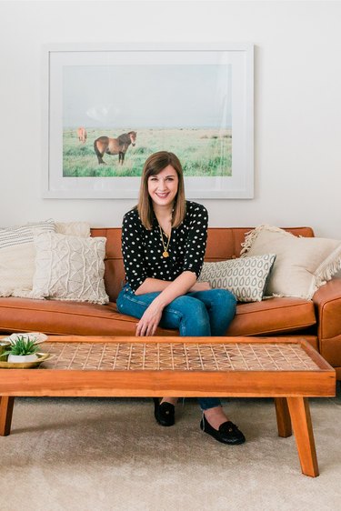 Person sitting in living room on leather couch with coffee table and art