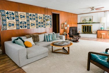 Living room with wood walls and floors with white rug and mid-century furniture and decor