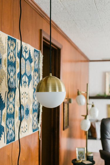 Wood wall with. blue-white tapestry and mid-century globe pendant lamps