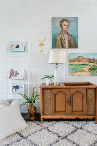 Vintage headboard on rug with paintings and plants