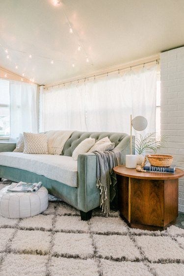 Living room with beige rug and turquoise sofa next to wood side table