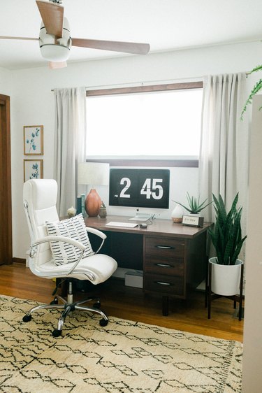 Office with tan rug, office chair, plant, and curtained window