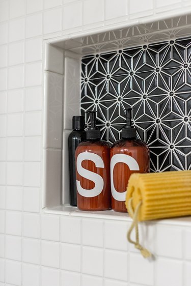 Shower niche with black geometric tile surrounded by white wall tiles