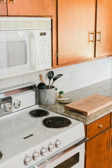 Wood kitchen cabinets, granite countertops and white tile backsplash with microwave and stovetop