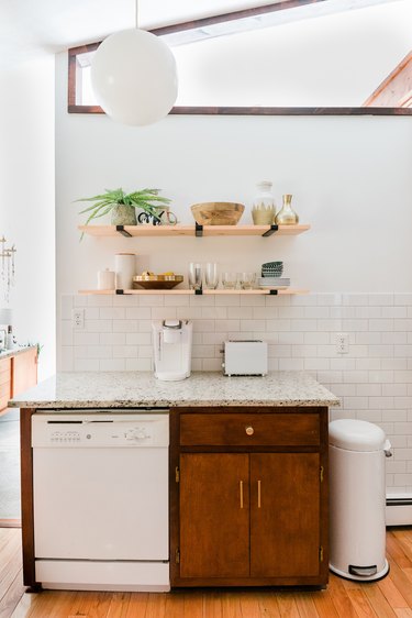 Kitchen with geometric window, pendant globe, glassware shelving and appliances