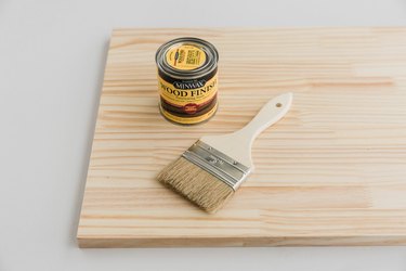 Paint brush and wood finish can on wood sheet against white background