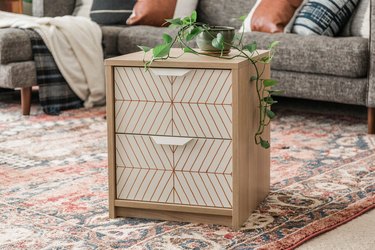 Scandinavian white and neutral nightstand with striped pattern and plant on Persian rug