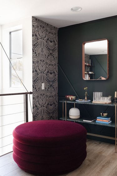 a corner of a room where a wall painted green meets one covered in an aztec-influenced silver pattern