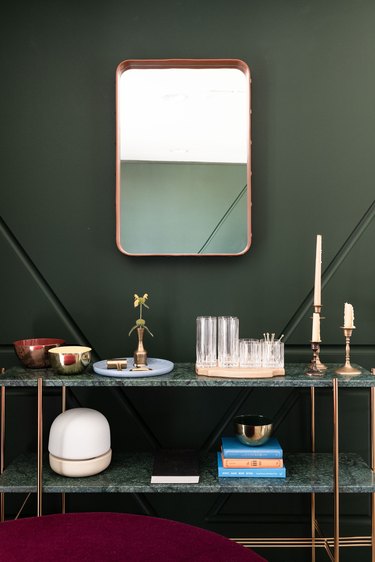 a deco-flavored set of marble shelves in front of a dark green wall