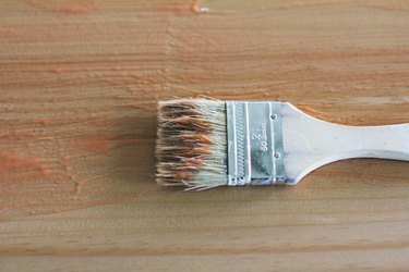 Detail of used white paintbrush resting on wooden surface