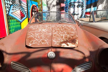 A brown retro car surrounded by colorful murals