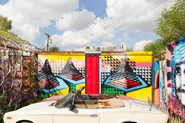 A retro white car in front of a colorful mural