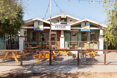 A white restaurant with wood picnic benches and a wood fence