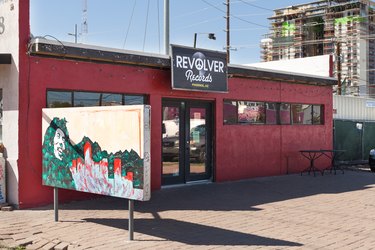 A red business with multiple windows and a mural in front