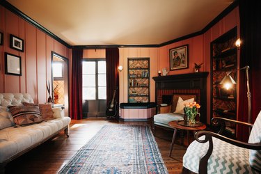 Ranch style living room with peach walls, wood floors, built-in bookshelves with paisley backing, and victorian seating