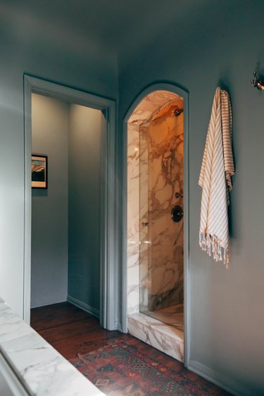 Blue painted walls with an arched entrance to a marble or granite shower
