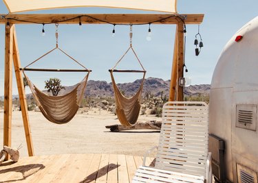 hanging chair hammocks in the desert next to an airstream