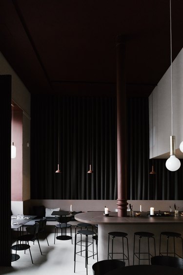 Dark minimalist bar with dark brown and black dining furniture and pendant lights