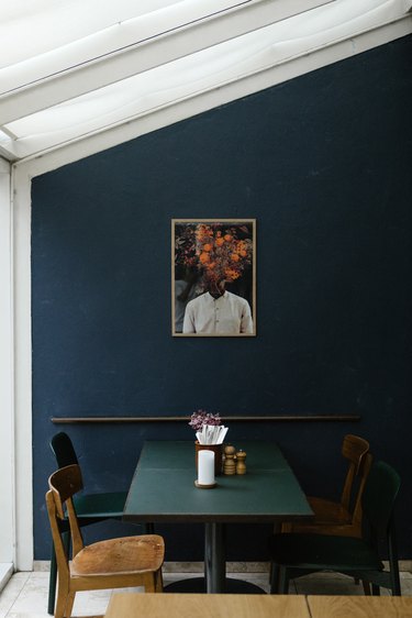 Skylights and blue wall with eclectic art over retro dining furniture