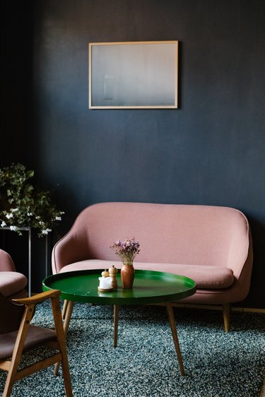 Retro pink sofa with green coffee table on green shag rug surrounded by blue wall