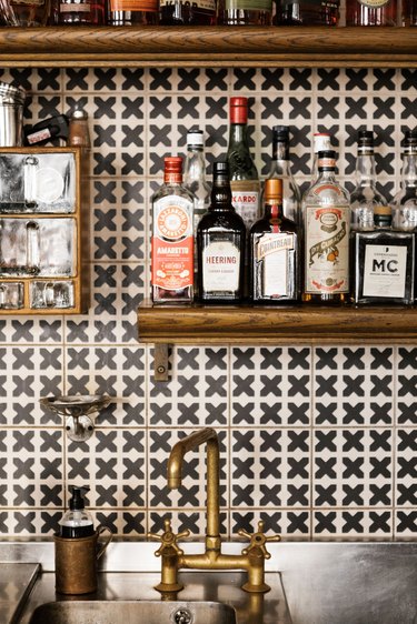 industrial bar idea with geometric backsplash, wood shelving, and industrial sink faucet