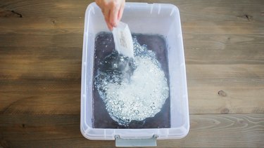Soda ash being added to bucket of indigo dye