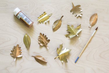 Painted gold paper leaves with paint brush and paint tube