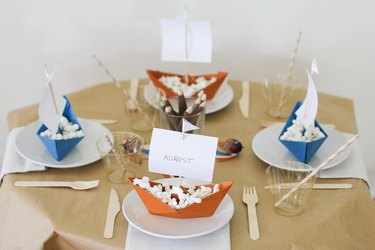 Kids dining table with folded paper boat decorations and disposable dishware