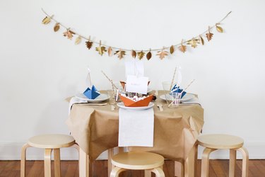 fall party idea with leafy garland, paper decor, and wood stools