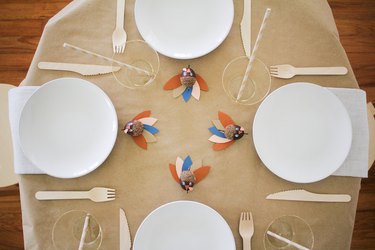 Dining table with paper tablecloth, wood utensils and paper-acorn turkey decor