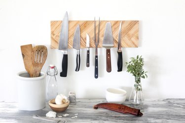 a knife holder made from magnets behind a layer of herringbone paint sticks mounted on a kitchen wall