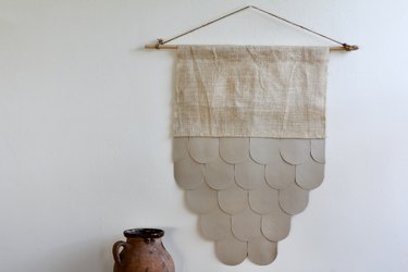 Boho leather and burlap wall hanging on white wall with decorative vase