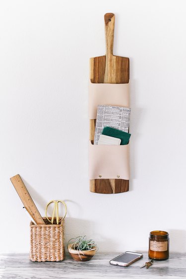 a wall-mounted letter holder made from a cutting board and leather strips