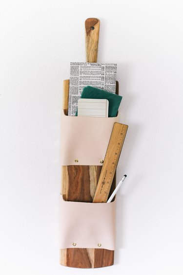 a wall-mounted letter holder made from a cutting board and leather strips