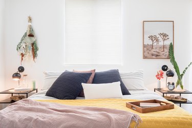 Bed with black-white-yellow bedding with plants and nightstand on either side