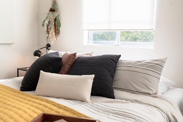 Bed with black and white pillows and yellow blanket