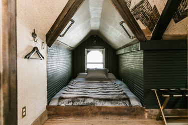 a sleeping nook with green walls, a bed on the floor, and a steeply sloped ceiling