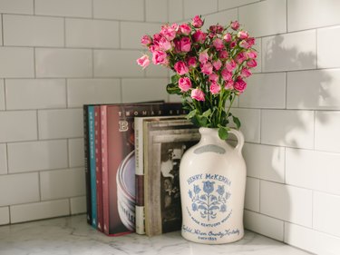 cookbooks and jug of fresh pink flowers on marble kitchen countertop